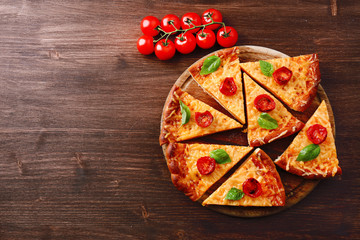 Slices of tasty cheese pizza with basil and cherry tomatoes on table close up