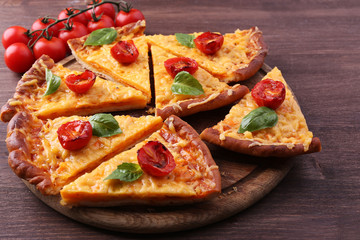 Slices of tasty cheese pizza with basil and cherry tomatoes on table close up