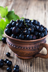 Blackcurrant in ceramic mug on rustic wooden board