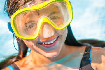 Naklejka premium Beautiful portrait of young smiling girl in the water with diving mask on her head