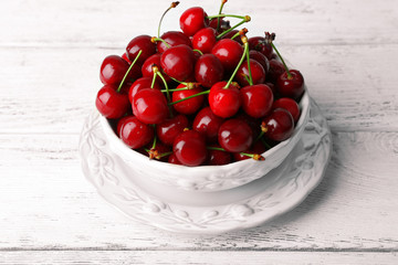 Sweet cherries in bowl on wooden table close up