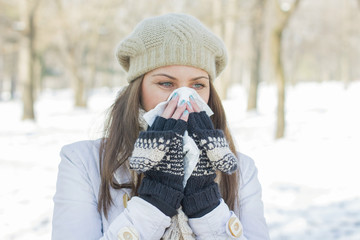 Young Woman in Winter Clothing Blowing Nose