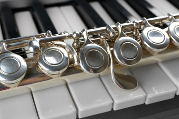 Obraz premium Silver flute keys and piano keyboard close-up classical music instrument detail musical education and performance, this composition highlights the connection between different musical instruments