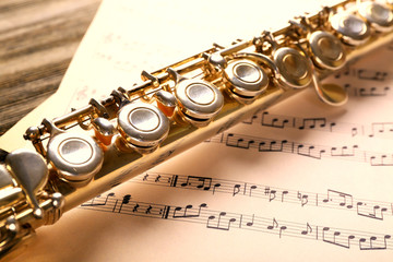 Fototapeta premium Silver flute with music notes on wooden table close up