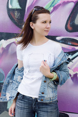 Portrait of young woman sitting at graffiti wall