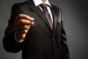 Businessman holding marker on gray background