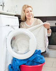 Elderly woman doing laundry with washing machine