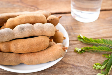 close up ripen sweet tamarinds in white disk put on wooden table