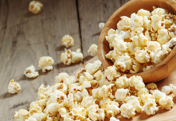 Caramel popcorn poured from a wooden bowl, selective focus