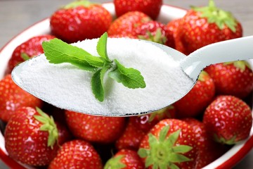 Steviapulver mit frischen Steviablättern auf einem Emaillelöffel über einer Schale frischer...