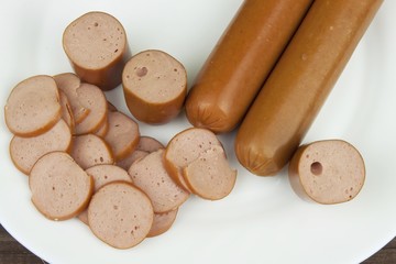 Detail of sliced chicken sausage lying on a porcelain plate. The structure of the poultry sausages. Homework snacks.