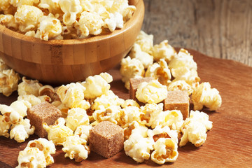 Caramel popcorn poured from a wooden bowl, selective focus
