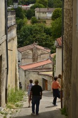 Touristes descendant une ruelle en forte pente depuis la haute ville de Saintes 
