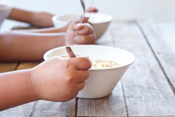 Children eating their  instant noodle in white bowl on wood tabl