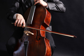 Man playing on cello on dark background © Africa Studio