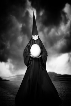 Strange person in black cloak with an egg