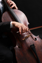 Man playing on cello on dark background
