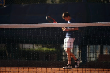 Jugador detrás de la red del campo de tenis