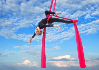 child hangs upside down on aerial silks in sky