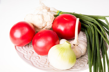 Tomatoes, garlic, onion and chive on plate isolated
