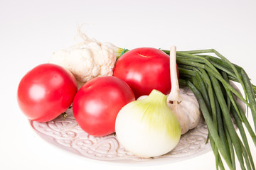 Tomatoes, garlic, onion and chive on plate isolated