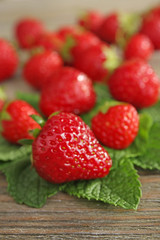 Ripe strawberries with leaves on wooden table, closeup
