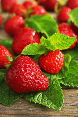 Ripe strawberries with leaves on wooden table, closeup