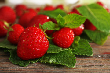 Ripe strawberries with leaves on wooden table, closeup