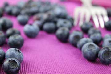 Blaubeeren mit zwei Gabel für Dessert auf lila Serviette
