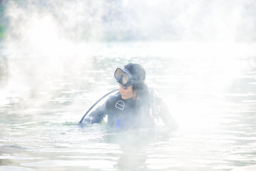 Woman diver in water shrouded in smoke