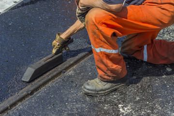Worker using a special tool to spread mastic asphalt