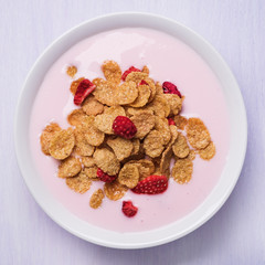 Yogurt with corn flakes and strawberry pieces, top view
