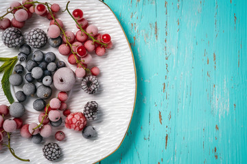 Frozen berries on a turquoise background with space for text