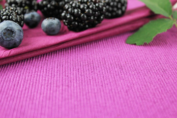 Brombeeren, Blaubeeren und Brombeerblätter auf lila Serviette