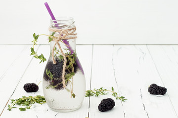 Healthy detox water with mulberry. Cold refreshing berry drink with ice and thyme on white wooden table. Copy space background