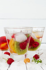 Healthy detox fruit infused flavored water. Summer refreshing homemade cocktail with fruits and thyme on white wooden table