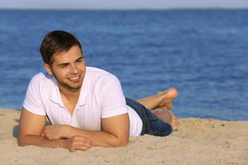 Fototapeta na wymiar Pretty guy lying on beach