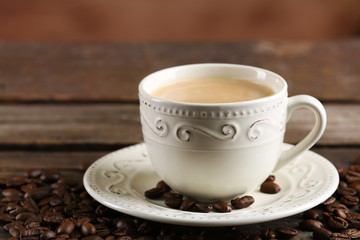 Cup of coffee and beans on wooden table close up