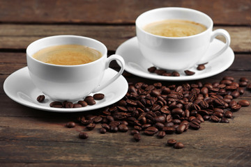 Cups of coffee and beans on wooden table close up