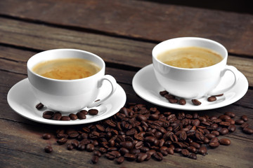 Cups of coffee and beans on wooden table close up