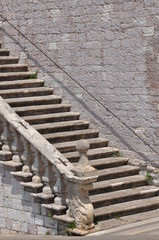 Fototapeta na wymiar Stone stairs along the high wall