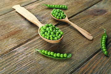 Fresh green peas in wooden spoon on table close up