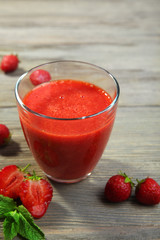 Glass of strawberry smoothie with berries on wooden table close up