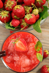 Glass of strawberry smoothie with berries on table close up
