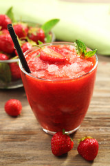 Glass of strawberry smoothie with berries on table close up
