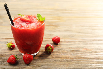 Glass of strawberry smoothie with berries on table close up