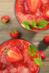 Glasses of strawberry smoothie with berries on table close up