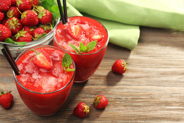 Glasses of strawberry smoothie with berries on table close up