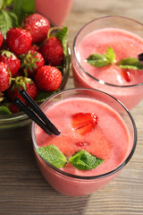 Glasses of milkshake with strawberries on wooden table close up
