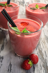Glasses of milkshake with strawberries on wooden table close up
